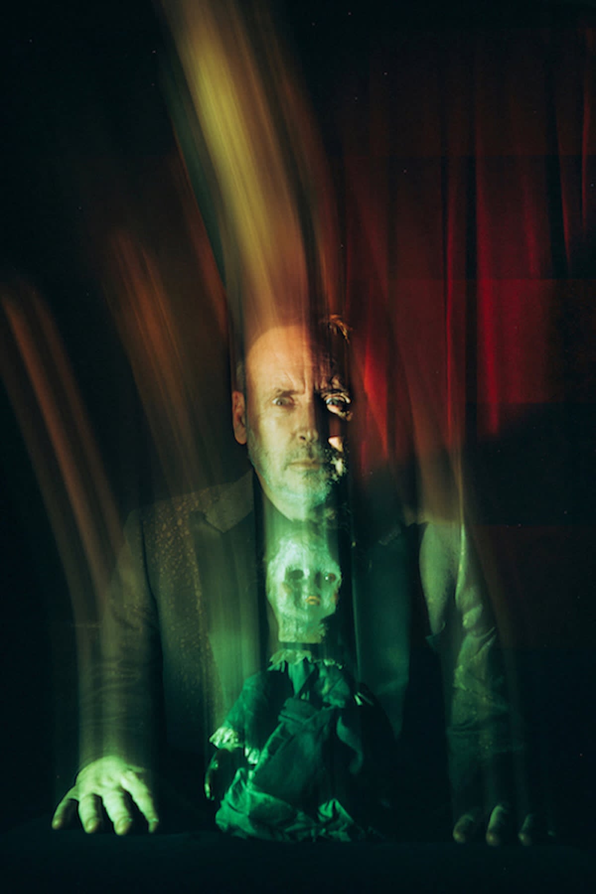 A long-exposure spirit photograph of Kevin Kopfstein with a ghostly doll materialising before him.